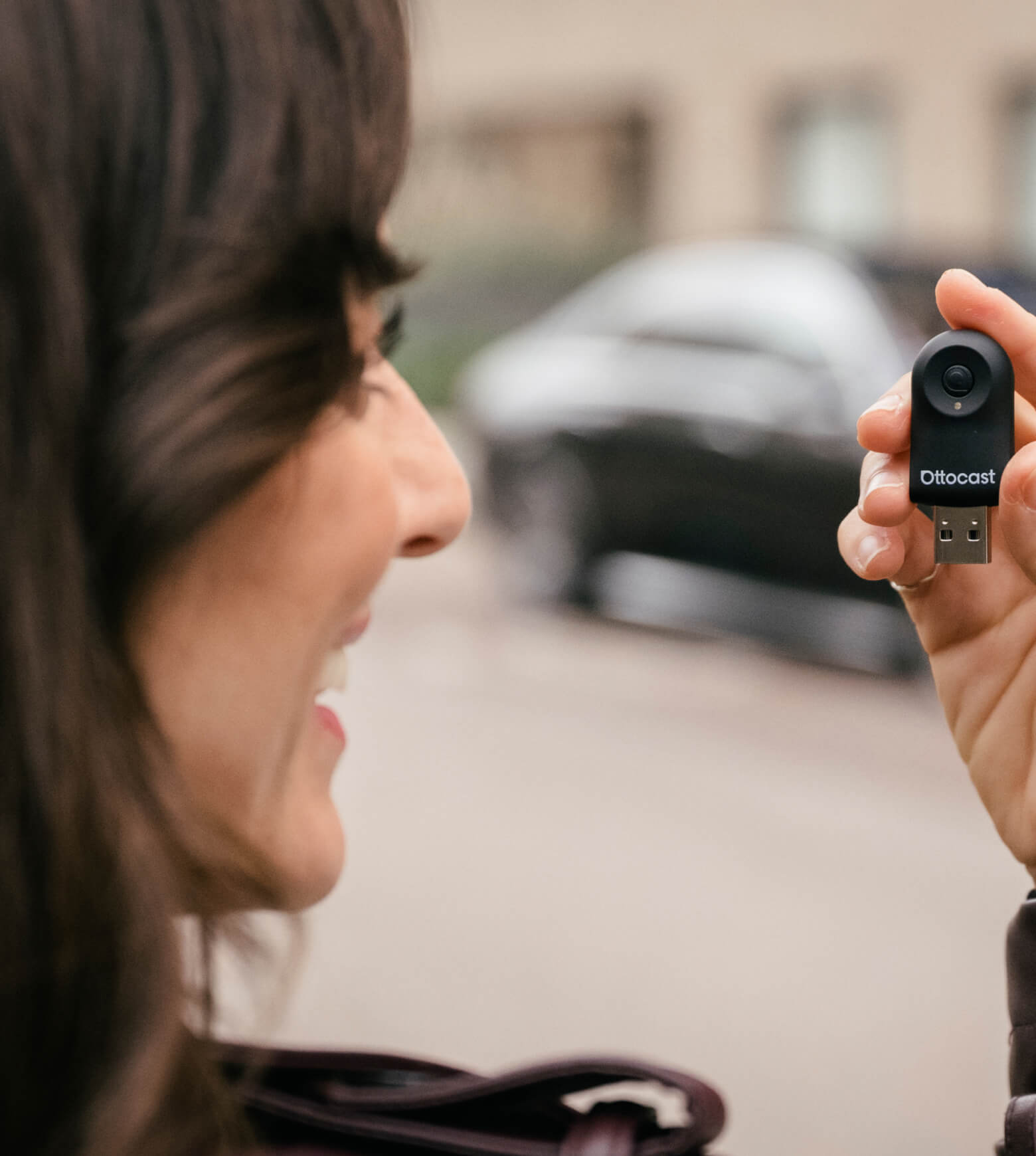 Woman holding Ottocast Mini wireless CarPlay and Android Auto adapter with compact USB design for easy in-car connection